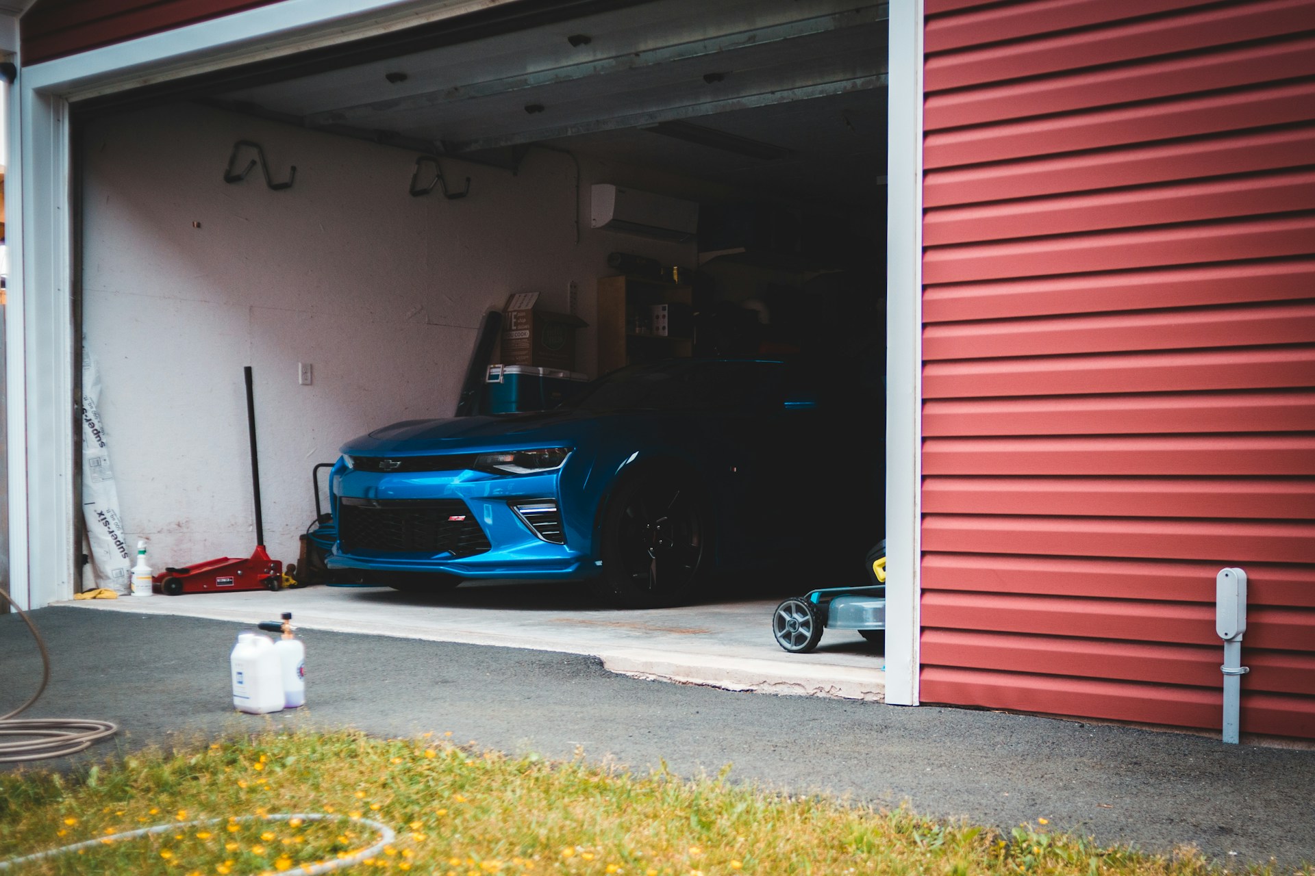 Blue sports car partially visible in a garage with red siding, showcasing a neat and organized workspace.