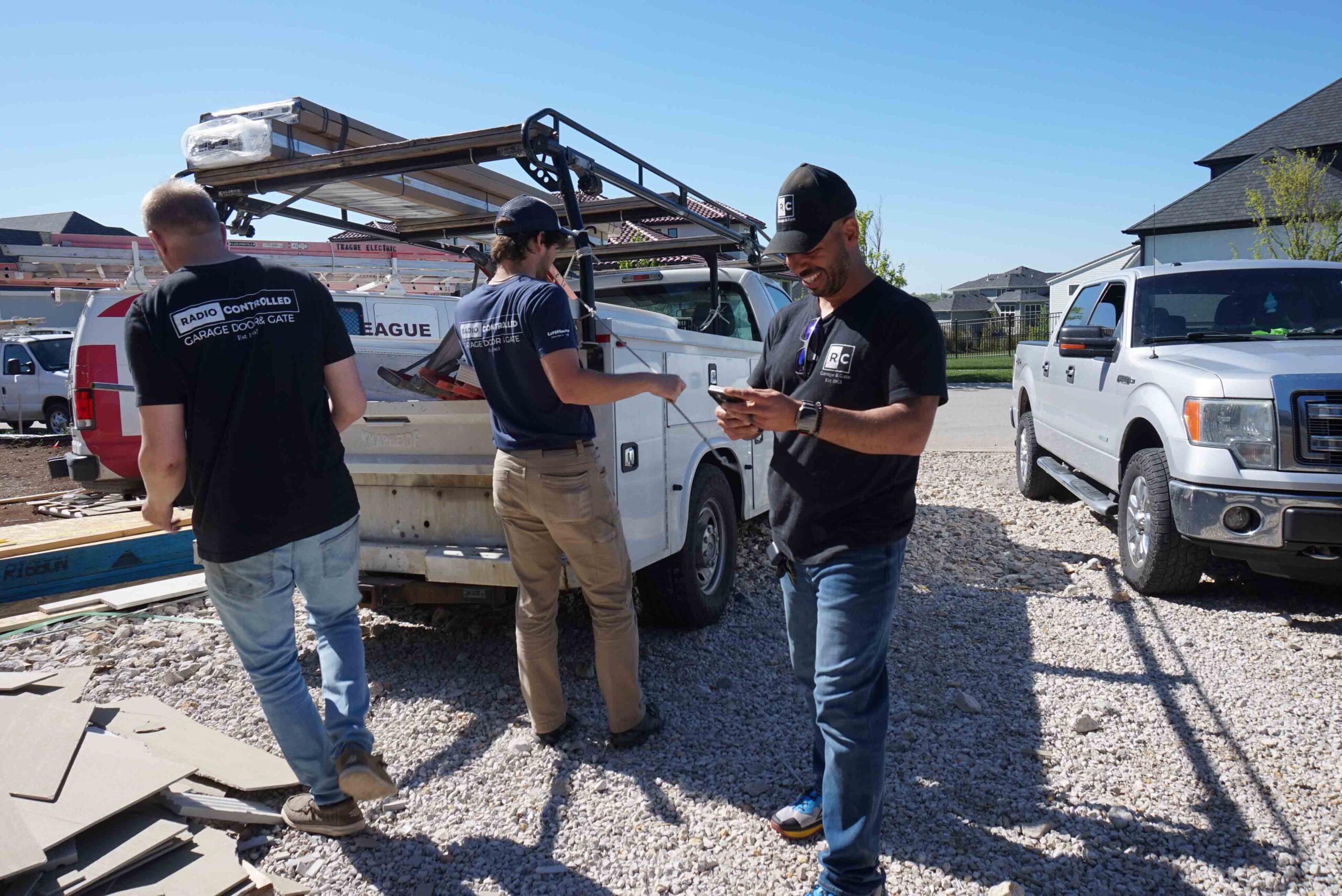 Three workers in branded shirts collaborate on a construction site, unloading materials from a pickup truck.