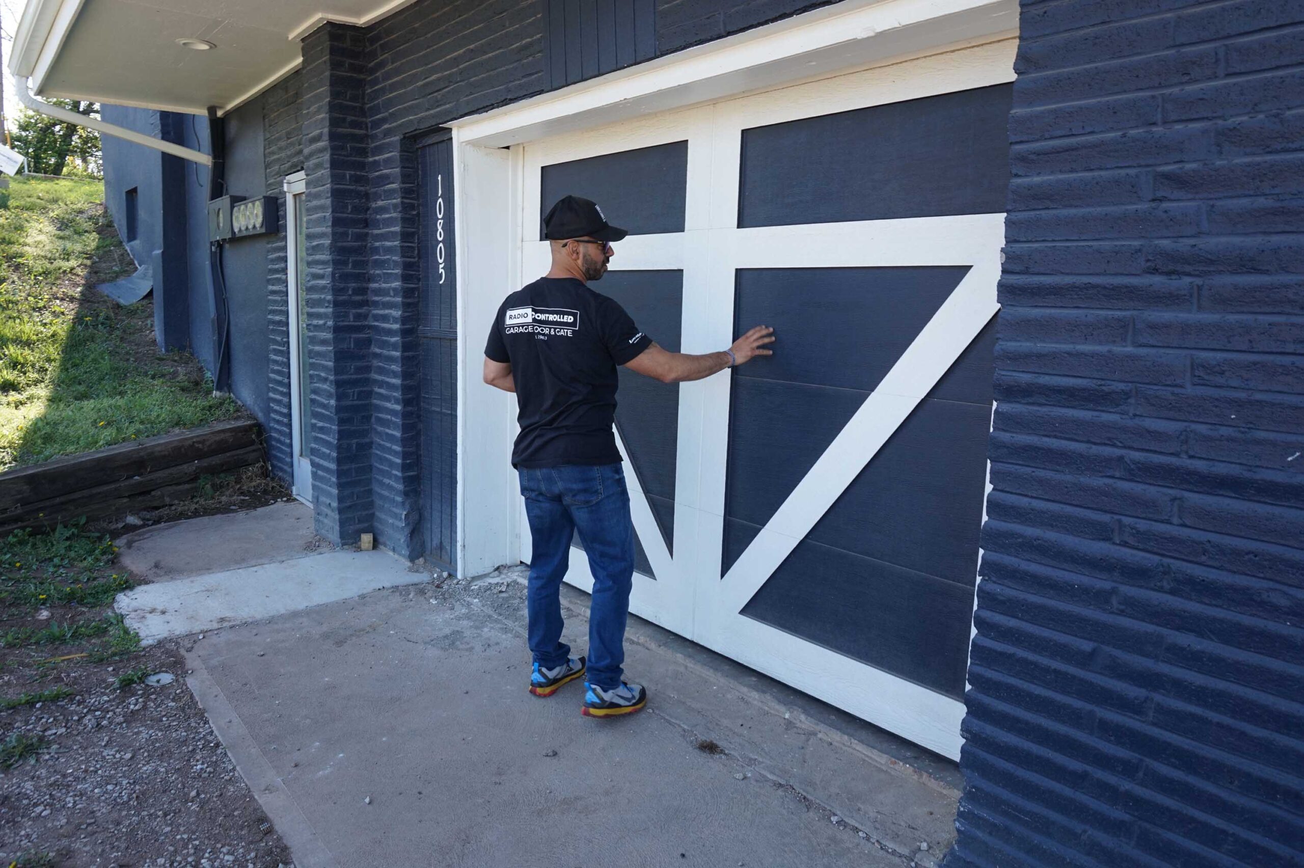 Man in a black shirt inspecting a stylish garage door, showcasing home improvement and maintenance.