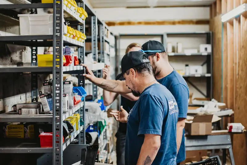 Technicians inspecting garage door parts in a warehouse for a garage door repair project.