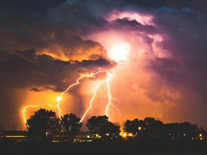 Dramatic lightning strikes illuminate dark storm clouds at night, showcasing nature's power and beauty.