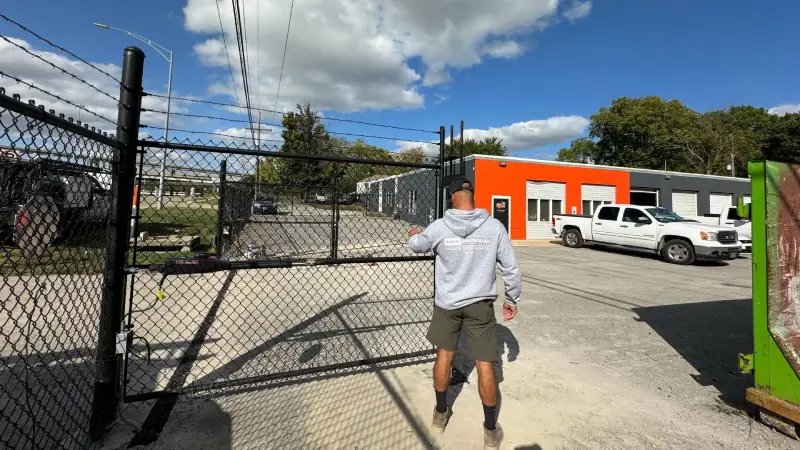 Professional garage door installation technician working on a secure chain-link gate for a commercial property.