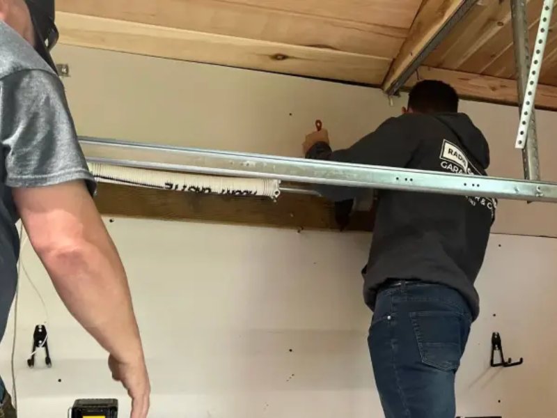 Two men work together to install shelving in a garage, highlighting DIY home improvement efforts.