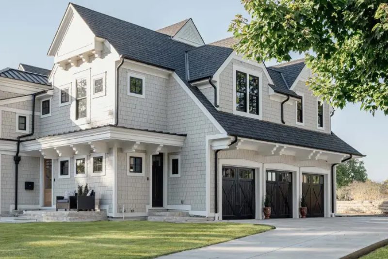 Three black garage doors on a modern gray home, highlighting the importance of functional garage door safety sensors.