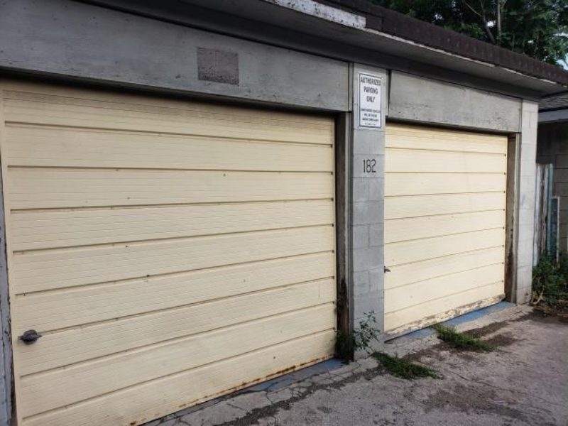 Aging tan commercial garage doors with rust and wear, illustrating the typical lifespan of exterior door panels.